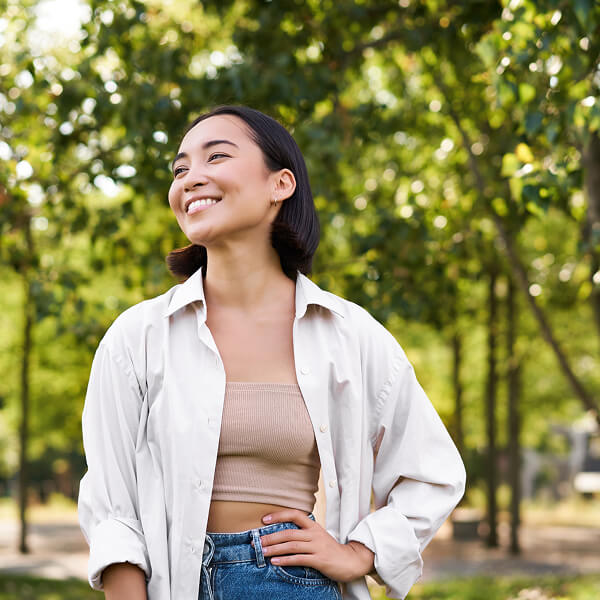 Smiling person standing outdoors with trees in the background